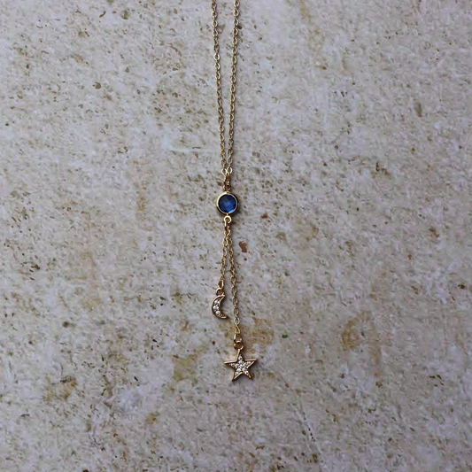Necklace with star and blue gemstone pendant on a textured beige surface