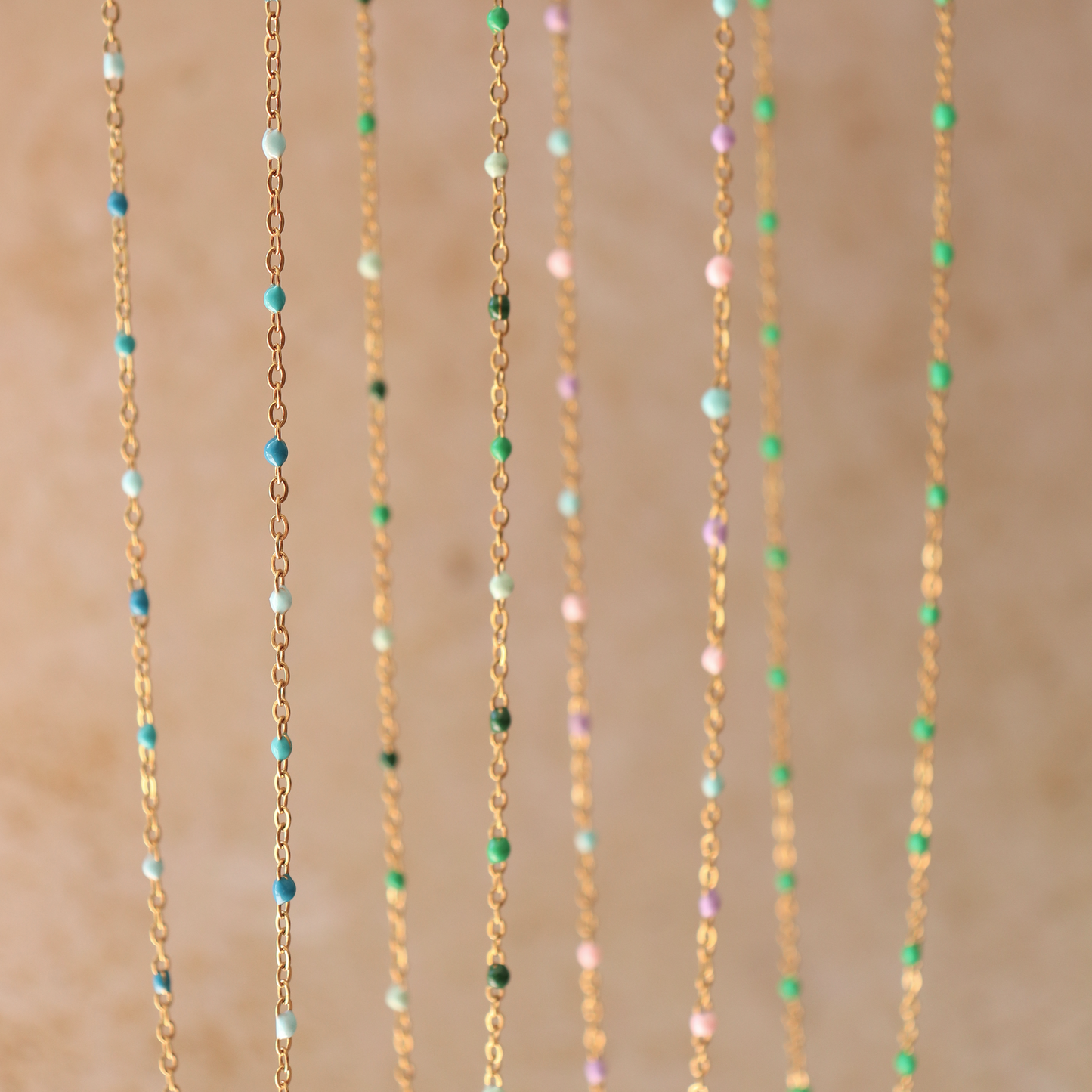Delicate gold chain necklaces with coloured glass beads in teal, green, lavender and blush hanging together