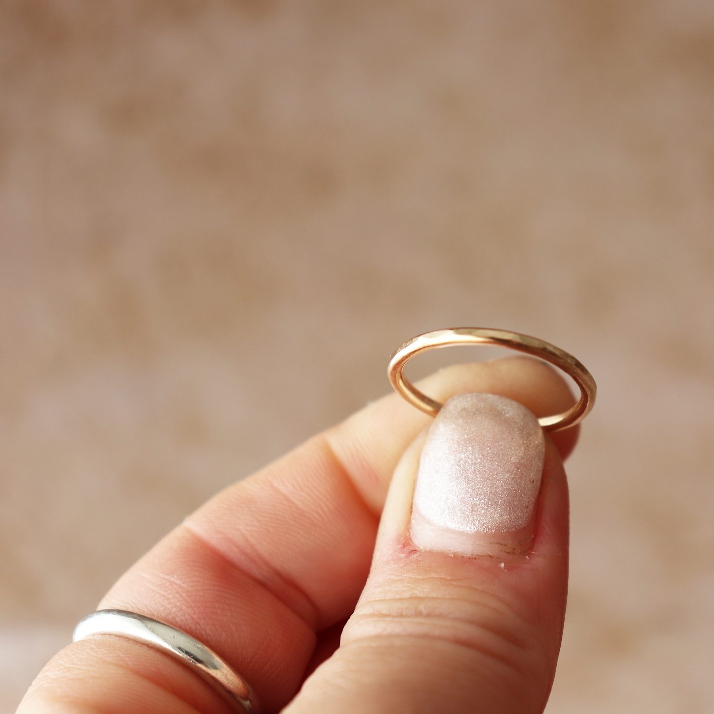 Gold filled hammered ring held between fingers